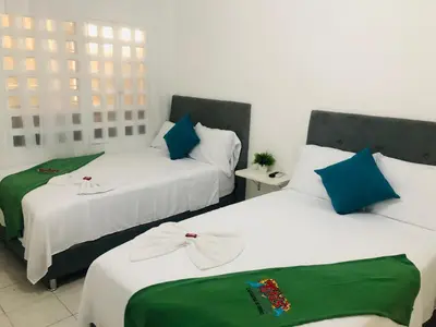 two beds with green and white sheets in a room at Tita’s Airport Hotel in Cartagena de Indias