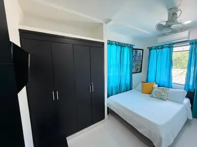 a small bedroom with blue curtains and a bed at Cabana Costa Azul in Coveñas