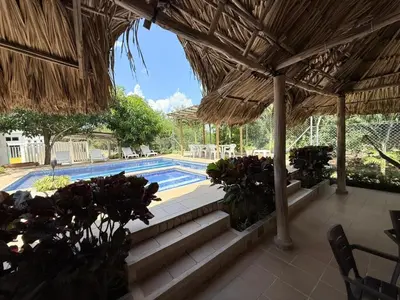 a swimming pool with stairs and a straw umbrella at Cabana Costa Azul in Coveñas