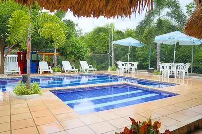 a swimming pool with tables and chairs and umbrellas at Cabana Costa Azul in Coveñas