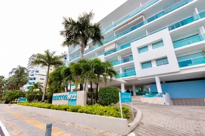 a building with palm trees in front of it at Edificio frente al mar con playas tranquilas in Cartagena de Indias