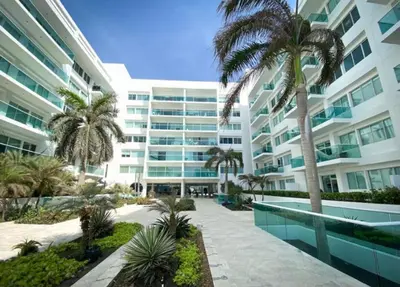 a large building with palm trees in front of it at Edificio frente al mar con playas tranquilas in Cartagena de Indias