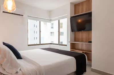 a bedroom with a bed and a flat screen tv at Apartamento en Bocagrande - Piscina, Jacuzzi y Mar in Cartagena de Indias