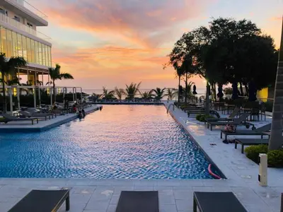 a swimming pool with chairs and a sunset in the background at Loft de Lujo - Wifi, piscina y mar in Santa Marta