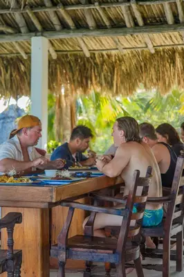 a group of people sitting at a wooden table at Hotel Isla Del Pirata in Isla del Pirata