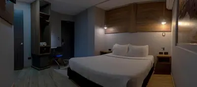 a hotel room with a white bed and wooden cabinets at The Blue Hotel in Cartagena de Indias