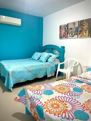 two beds in a bedroom with blue walls at San José Beach in Lomarena