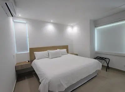 a bedroom with a white bed and two windows at Atlantis Suites -Amoblados Nuevos sector Buenavista in Barranquilla