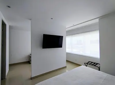 a white bedroom with a television on a wall at Atlantis Suites -Amoblados Nuevos sector Buenavista in Barranquilla