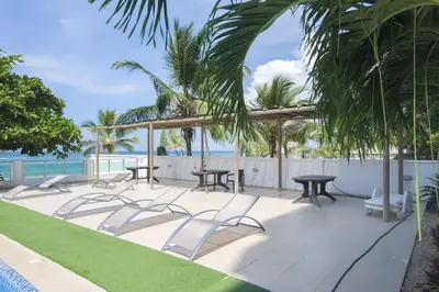 a patio with tables and chairs and the ocean at Magico Apartamento Frente al Mar 2 Habitaciones B22B in Coveñitas