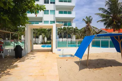 a building on the beach with a blue open door at Magico Apartamento Frente al Mar 2 Habitaciones B22B in Coveñitas