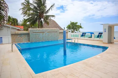 a blue swimming pool with a view of the ocean at Magico Apartamento Frente al Mar 2 Habitaciones B22B in Coveñitas