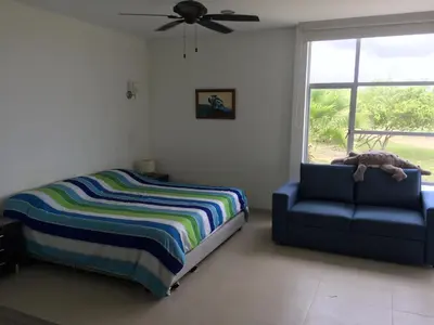 a bedroom with a bed and a couch and a window at Casa de Playa en Marina Puerto Velero in Barranquilla