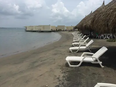a row of white chairs sitting on the beach at Casa de Playa en Marina Puerto Velero in Barranquilla
