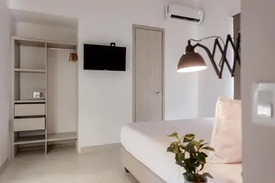 a white bedroom with a bed and a tv at Ganem Suites Cartagena in Cartagena de Indias