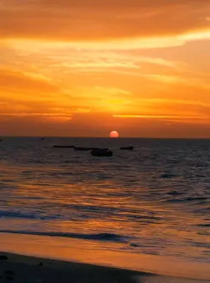 a sunset on the beach with boats in the water at APARTA-SUITES EN CARTAGENA JUNTO a LA PLAYA in Cartagena de Indias