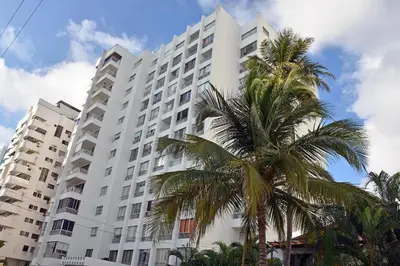 a large white building with a palm tree in front of it at APARTA-SUITES EN CARTAGENA JUNTO a LA PLAYA in Cartagena de Indias