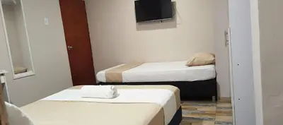 two beds in a small room with a tv at Hotel Gran Mendoza Inn Barranquilla in Barranquilla