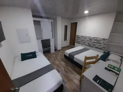 a small room with two beds and a television at Hotel Gran Mendoza Inn Barranquilla in Barranquilla