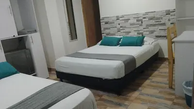 a bedroom with two beds with blue pillows at Hotel Gran Mendoza Inn Barranquilla in Barranquilla
