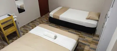 a small room with two beds and a bench at Hotel Gran Mendoza Inn Barranquilla in Barranquilla