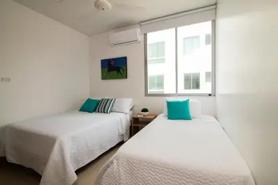 two beds in a white room with a window at Magico Apartamento Frente al Mar 3 Habitaciones PAZ222 in Coveñitas
