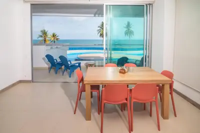 a dining room with a table and chairs and the ocean at Magico Apartamento Frente al Mar 3 Habitaciones PAZ222 in Coveñitas