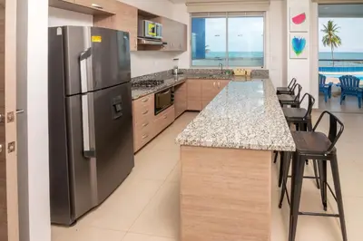 a kitchen with a stainless steel refrigerator and a table at Magico Apartamento Frente al Mar 3 Habitaciones PAZ222 in Coveñitas