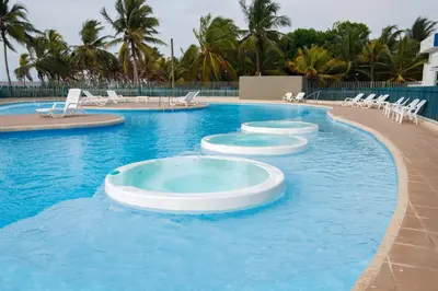 a large swimming pool with white chairs in the water at Magico Apartamento Frente al Mar 3 Habitaciones PAZ222 in Coveñitas