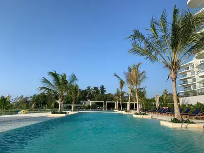 a swimming pool with palm trees and a building at Morros ío Serena Del Mar - RNT 95283-523 in Cartagena de Indias