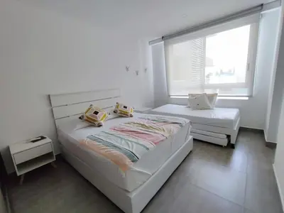 a white bedroom with two beds and a window at Spiaggia di Cartagena primera línea de playa in Cartagena de Indias