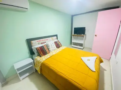 a bedroom with a yellow bed and a tv at House Marfito Airport in Cartagena de Indias