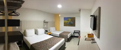 a hotel room with two beds and a flat screen tv at Hotel Genova Prado in Barranquilla