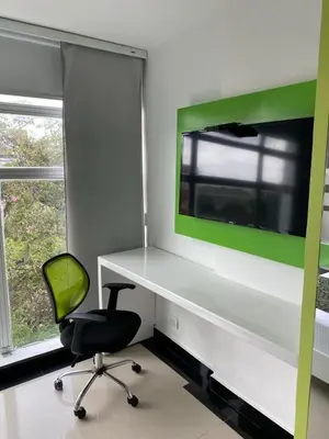 a office with a desk and a chair and a television at Hotel Genova Prado in Barranquilla