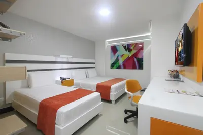 a hotel room with two beds and a desk at Hotel Genova Prado in Barranquilla