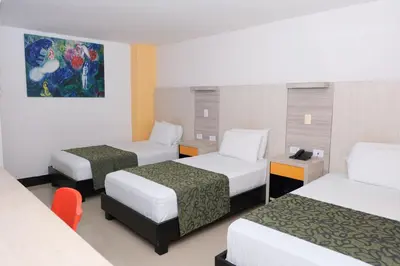 a hotel room with three beds and a painting on the wall at Hotel Genova Prado in Barranquilla