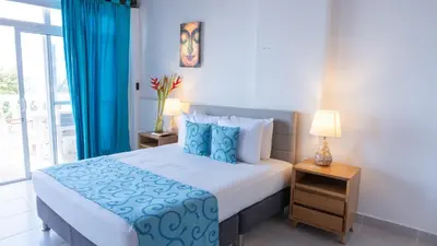 a bedroom with a bed with blue sheets and a window at hotel 3 banderas Manzanillo del Mar in Cartagena de Indias