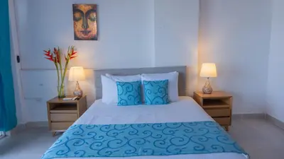 a bedroom with a bed with blue pillows and two lamps at hotel 3 banderas Manzanillo del Mar in Cartagena de Indias