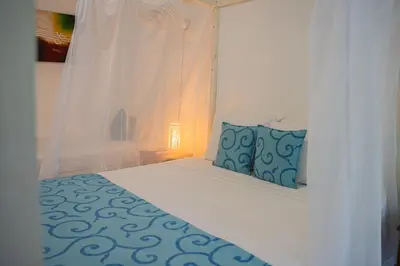 a white bed with two blue pillows on it at hotel 3 banderas Manzanillo del Mar in Cartagena de Indias