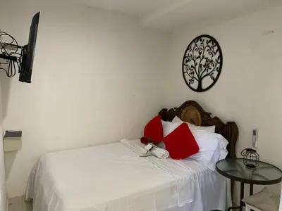 a bedroom with a white bed with red pillows and a table at Hostal Marbella 47 in Cartagena de Indias