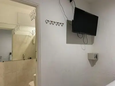 a bathroom with a tv on the wall next to a toilet at Hostal Marbella 47 in Cartagena de Indias