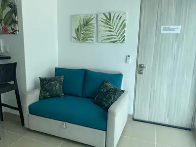 a blue couch with two pillows sitting in a room at Apartamento dentro del Hotel Sonesta Cartagena, aprovecha estar en lo mejor de MORROS in Cartagena de Indias