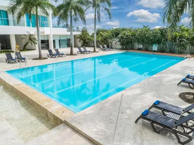 a swimming pool at a resort with chairs and palm trees at Apartamento dentro del Hotel Sonesta Cartagena, aprovecha estar en lo mejor de MORROS in Cartagena de Indias