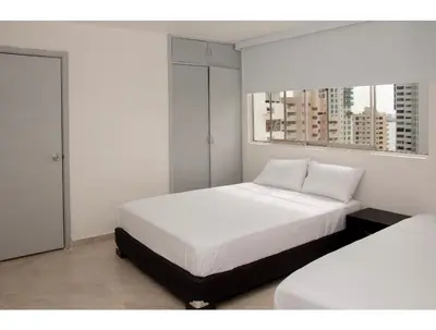 a white bedroom with two beds and two windows at III NICE 2 BEDROOM APARTMENT Bocagrande in Cartagena de Indias