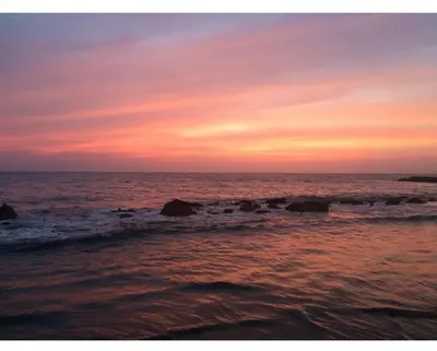 a sunset over the ocean with rocks in the water at III NICE 2 BEDROOM APARTMENT Bocagrande in Cartagena de Indias