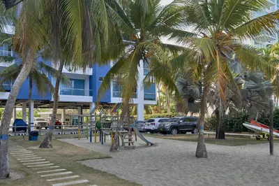 a playground with palm trees in front of a building at Hermoso Apartamento Frente al Mar 2 Habitaciones PAZ148 in Coveñitas