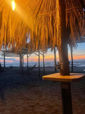 a beach with a straw umbrella and a table on the beach at älanacasadeplaya in San Bernardo del Viento