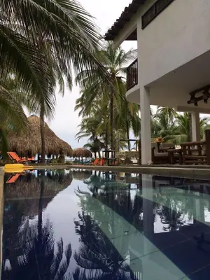 a swimming pool next to a resort with palm trees at älanacasadeplaya in San Bernardo del Viento