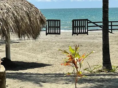 two benches sitting on the beach near the ocean at älanacasadeplaya in San Bernardo del Viento