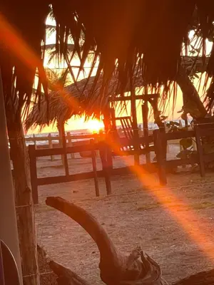 a view of the sun setting behind benches on the beach at älanacasadeplaya in San Bernardo del Viento